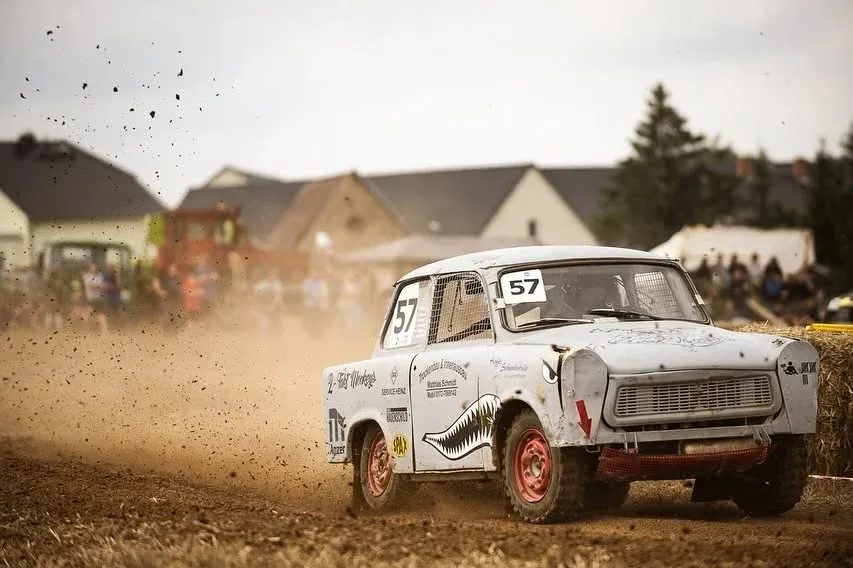 Trabant mit der Startnummer 57 wirft auf dem Acker Erde auf, dahinter Zuschauer