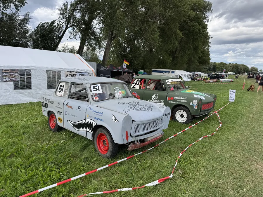 Grauer Trabant mit der Startnummer 51 und ein olivgrüner Trabant mit der Startnummer 20 nebeneinander im Fahrerlager