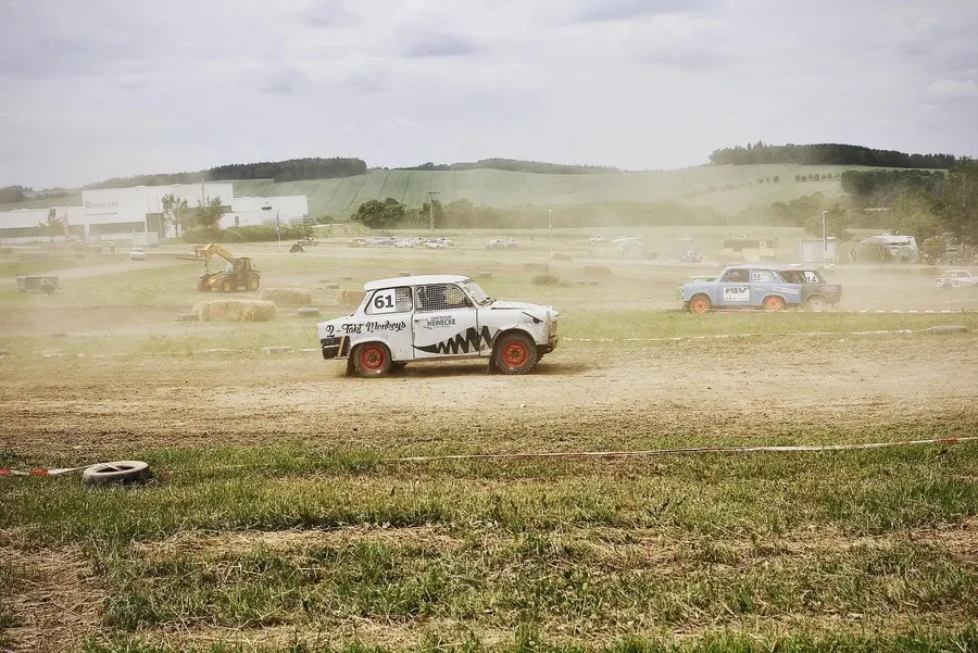 Trabant mit der Startnummer 61 in Seitenansicht auf staubiger Strecke, im Hintergrund weitere Fahrzeuge
