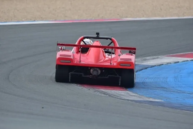 Roter Radical SR3 von hinten am Kurvenausgang, daneben die blau-weißen Randsteine der Strecke