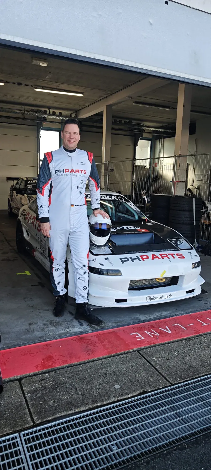 Patrick Schmechel im Rennanzug mit Helm in der Hand vor seinem Toyota MR2 in der Box