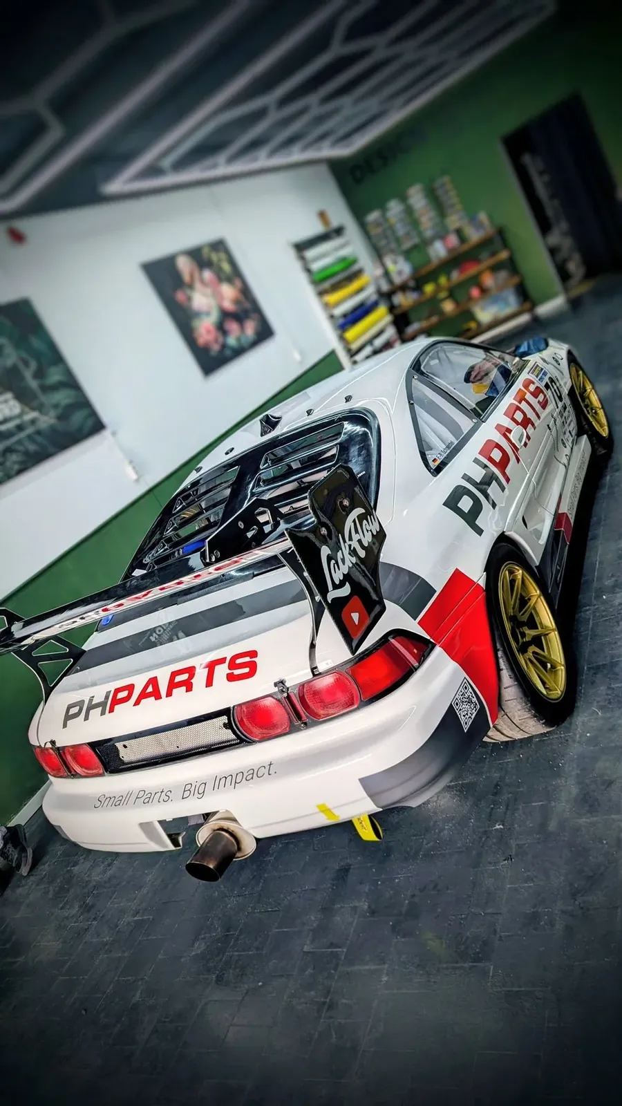 Heckansicht des weißen Toyota MR2 mit Doppelflügel in der Werkstatt vor grüner Wand